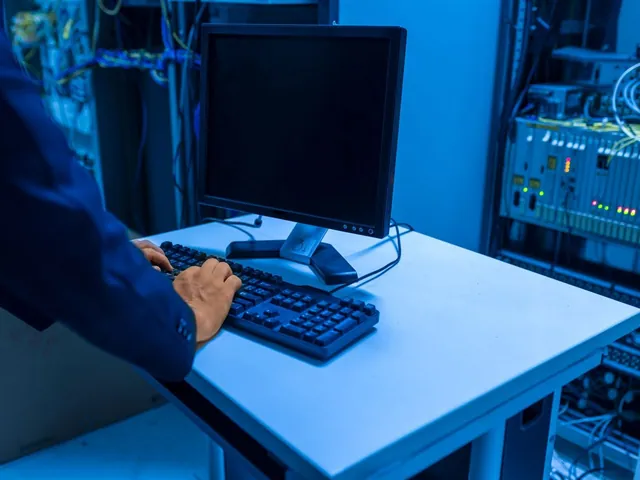 An IT specialist working at a workstation in a server room